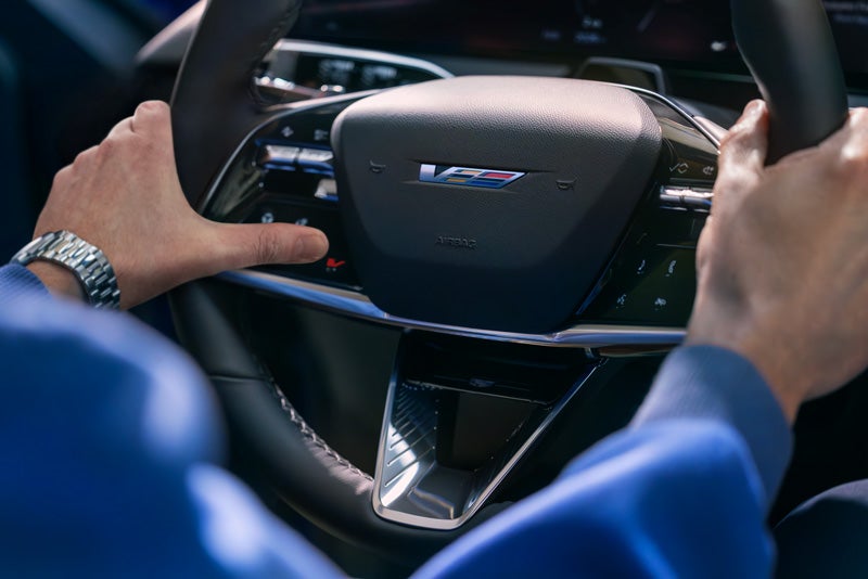Close-up of a Man About to Press the V-Button on the 2026 OPTIQ-V Steering Wheel | Parker Cadillac in Little Rock AR