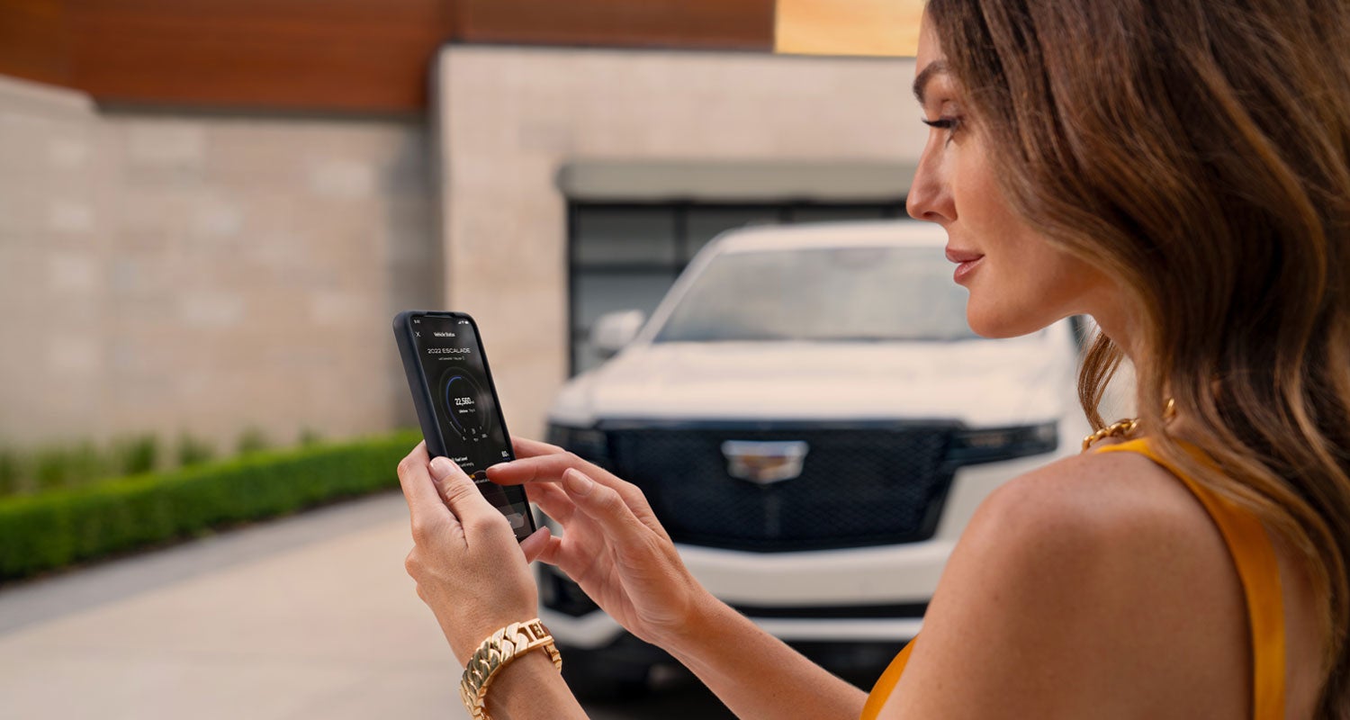 lady checking her mobile with a Cadillac vehicle background | Parker Cadillac in Little Rock AR